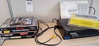 Console, games stack, remote, manual and cables on shelf