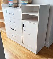 Front view of white dresser/changing table showing four drawers, cabinet door, open shelf