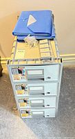 Front view of stackable four-drawer plastic storage with accessories on top