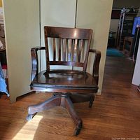 Front view of wood swivel bankers chair showing slat back and seat