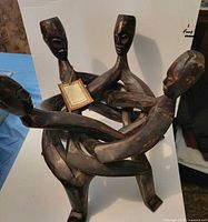 front view of interlocking wood sculpture showing four heads and arms