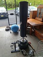 Full view of freestanding punching bag on base with gloves and pedal exerciser nearby