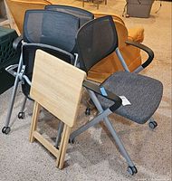 Three Allsteel Seek chairs nested together with folding tray table in front