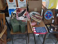 Group shot showing ammo cans, bench, flags, posters, plate, plaque