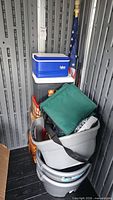 Stack showing Igloo cooler, gray Ozark Trail cooler, green soft cooler bag, nested gray tubs, U.S. flag on pole