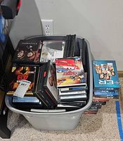 Plastic tote filled with assorted single-title DVDs and box sets including Cars and Titanic
