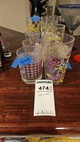 Group of assorted tall and short printed glasses on bar top