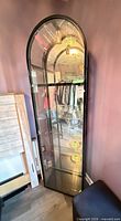 Full view of black metal and glass curio cabinet with arched top