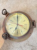 Front view of brass and copper ship’s clock showing dial and lugs
