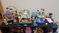 Assortment of Disney snow globes and figurines displayed on shelf