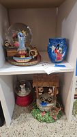 Overall view showing Tinker Bell globe, Sorcerer Mickey cup, Mickey snowman globe, Mickey & Minnie wishing well figurine