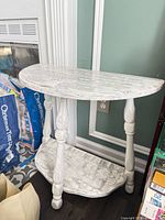 Front view of two-tier distressed white demilune side table
