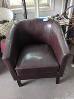 Front view of burgundy faux leather tub chair showing overall form, cushion, and legs
