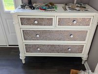 Front view of dresser showing four drawers with fabric panels and knobs