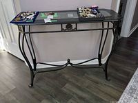 Full view of console table front showing glass top, metal base, wood veneer trim