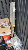 Folded aluminum work platform leaning against container, tag 347 visible