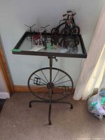 Full view of metal accent table with glass top and tricycle figurines