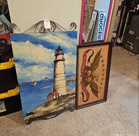 Both framed artworks: lighthouse painting on stand, eagle print beside it