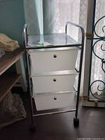Front view of chrome frame cart with three white drawers on wheels