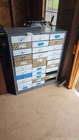 front view of gray metal cabinet with patterned and white drawer fronts