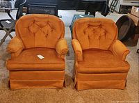 Front view of both matching orange velvet tufted armchairs