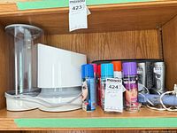 Shelf view showing Vornado humidifier, five hair color spray cans, massager handles visible, cords