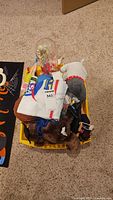 Overview of yellow bin filled with plush toys, NASA bag, astronaut dome, other small toys