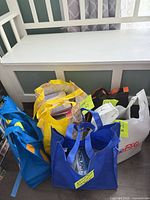 Six tote bags on floor next to bench, containing CDs