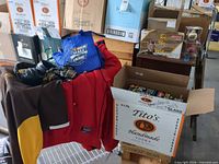 Apparel, headphones and boxed ornaments on open Tito's Vodka carton