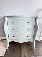 Front view of bombe dresser showing three drawers and knobs