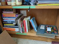 Shelf with stacked paperbacks, stamp albums and pamphlets