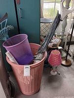 Basket containing steam mop handle, purple waste bin, visible lamp beside