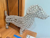 Full side view of silver metal dachshund figurine with glass crystals