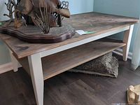 Full view of coffee table showing top, lower shelf, decorative item on top