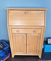 Front view of solid wood secretary desk showing drop-front panel, single drawer, lower cabinet doors