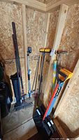 Assorted shovels, rakes and broom standing in shed corner