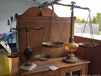Two brass and glass balance scales on wooden surface