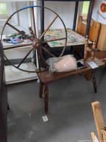 overall view of wooden spinning wheel on legs with cone of yarn on bench