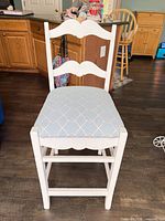 Front view of white ladder-back chair showing light-blue upholstered seat