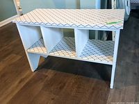 Front view of white MDF storage bench showing three cubbies and patterned surfaces