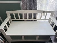 Full view of white wood storage bench showing slatted back and hinged seat