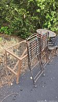 Two folding wrought iron bar-height chairs, metal table base, round perforated tabletop visible