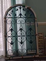 Front view of arched wrought iron and wood window trellis