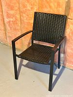 Front angled view of the chair showing wicker seat and metal arms