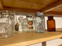 All seven vintage glass containers on shelf