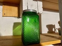 Front view of green ribbed glass jar with metal lid