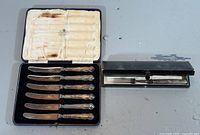 Open presentation case showing six butter knives and travel set case