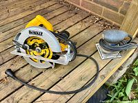 Circular saw and palm sander on wooden deck