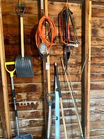 Full view of wall showing shovels, level, extension cord, bow saws and stakes