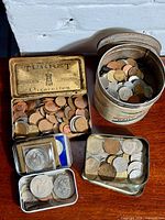 Overview showing three tins filled with assorted world coins